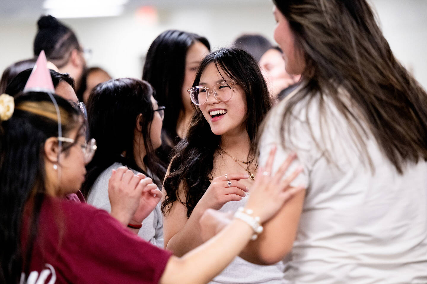 A group of young people are laughing and interacting joyfully at what appears to be a social gathering.